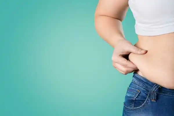 Image of woman pinching her love handles to show weight gain Somerset