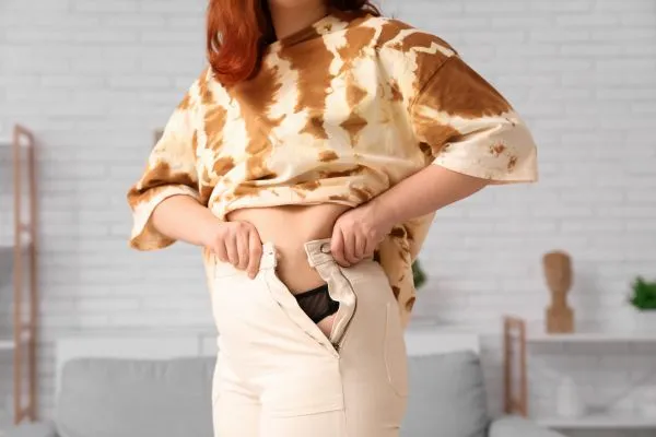 Image of woman trying to do her trousers up after pregnancy weight gain Somerset