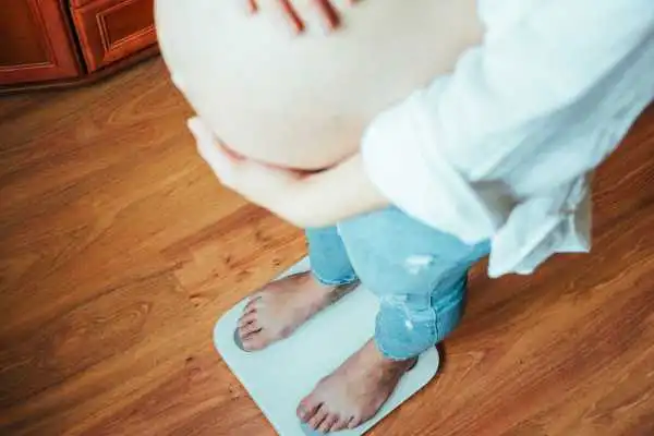 Image of woman weighing herself and experiencing weight gain through pregnancy Somerset
